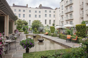 A courtyard with outdoor seating, a water feature, and well-maintained greenery.