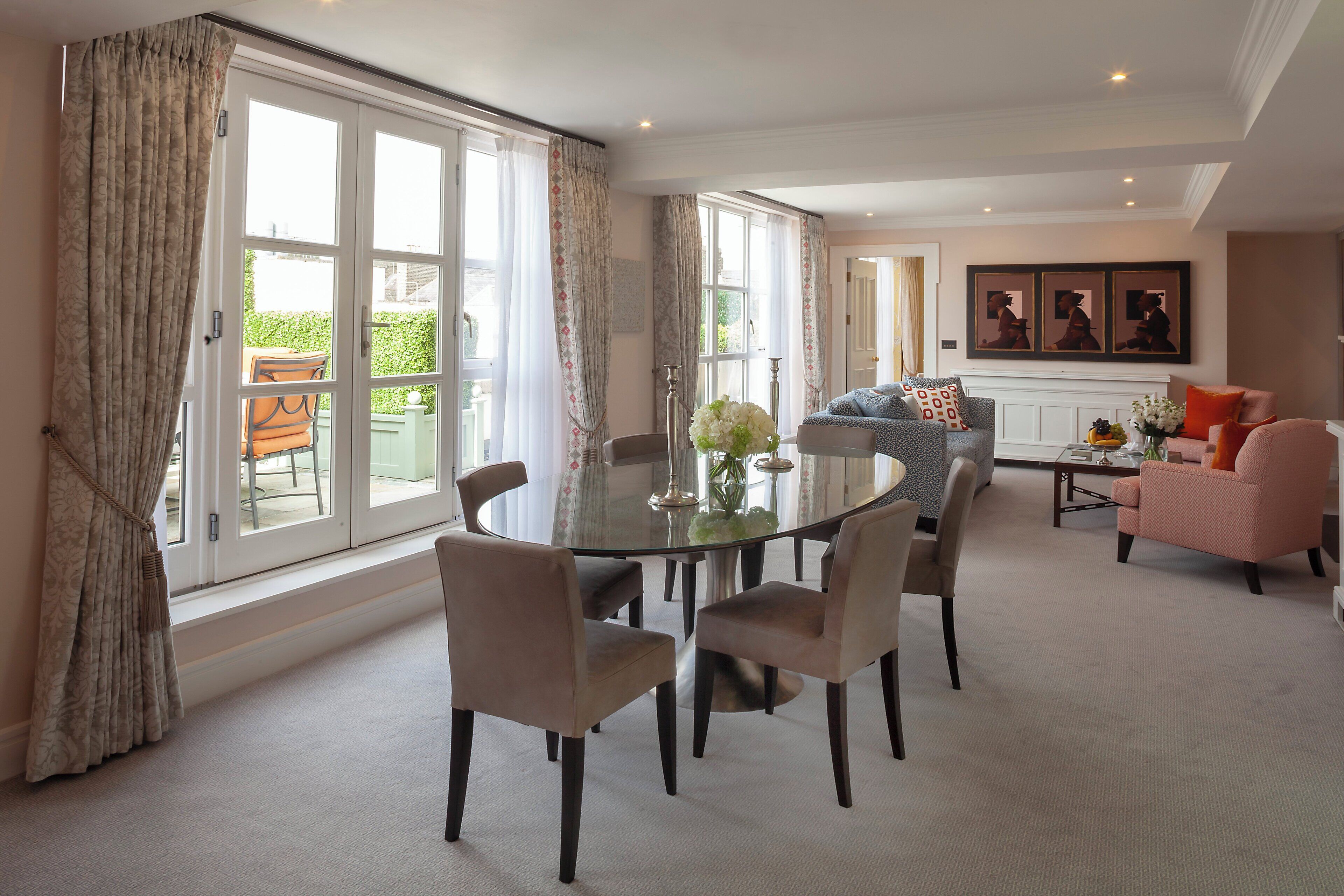 A spacious living room with a round glass table surrounded by chairs, a sofa, and a coffee table.