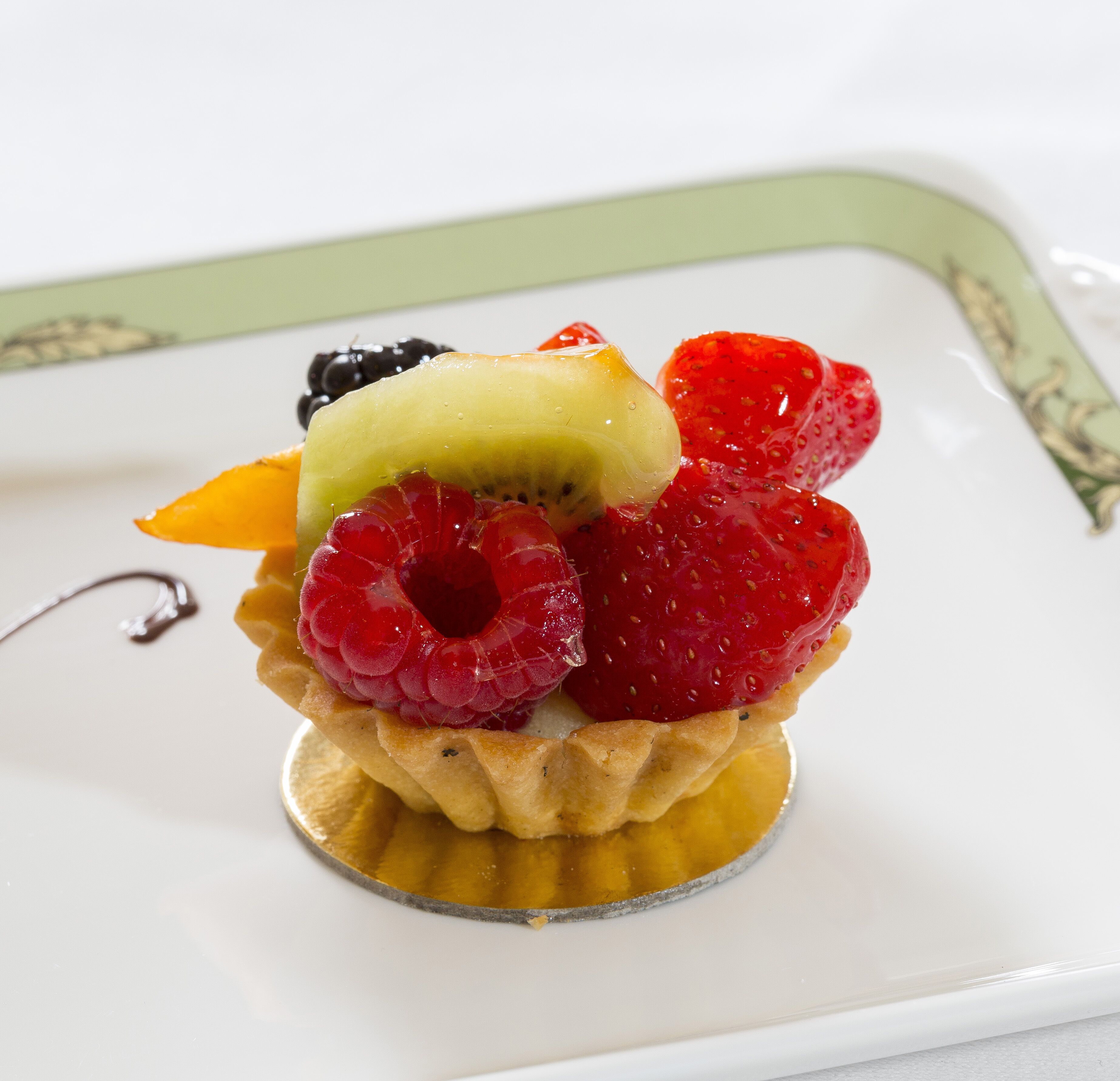 Un postre con una tarta de frutas sobre un plato blanco.