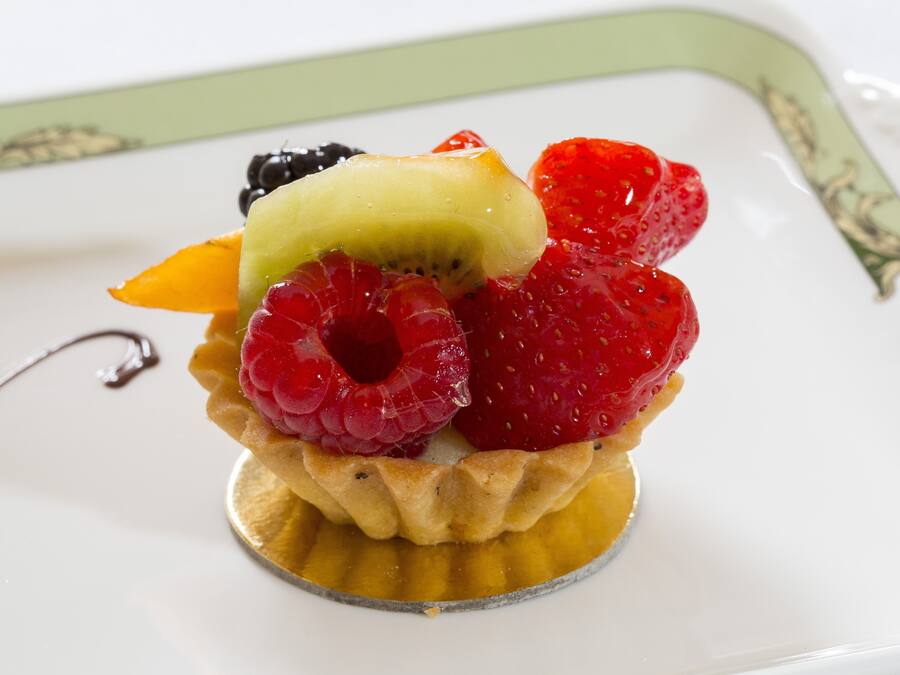 Un postre con una tarta de frutas sobre un plato blanco.