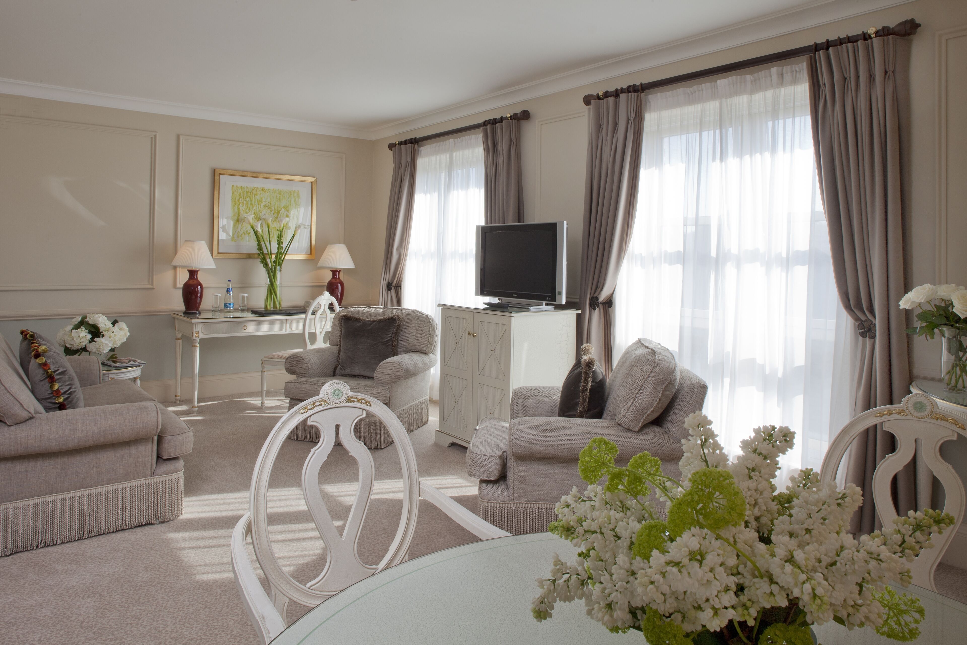 Una sala de estar bien iluminada con televisor, sofás, una mesa de comedor y un jarrón decorativo.