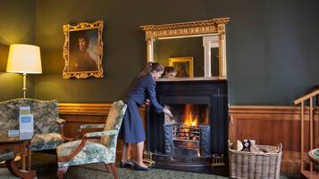 Una habitación con chimenea, un retrato enmarcado y una lámpara.
