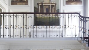 A grand hall with a high ceiling, ornate columns, and a balcony with a wrought iron railing. - The Merrion (Dublin)