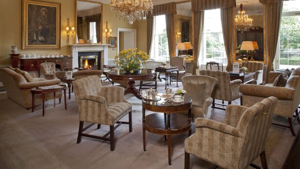 A spacious living room with multiple armchairs, a fireplace, and a chandelier. - The Merrion (Dublin)