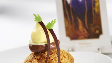 Un postre con salsa de chocolate y un pequeño adorno verde sobre un plato blanco.
