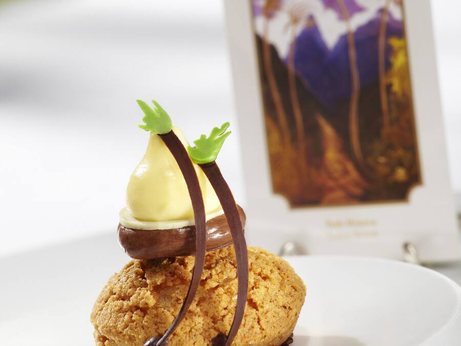 Un postre con salsa de chocolate y un pequeño adorno verde sobre un plato blanco.
