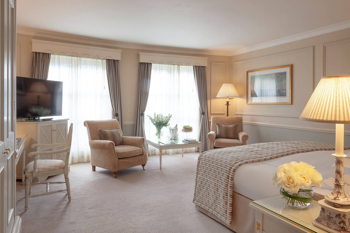 Una camera d'albergo con un letto, due poltrone, una televisione, una lampada e un quadro appeso al muro.