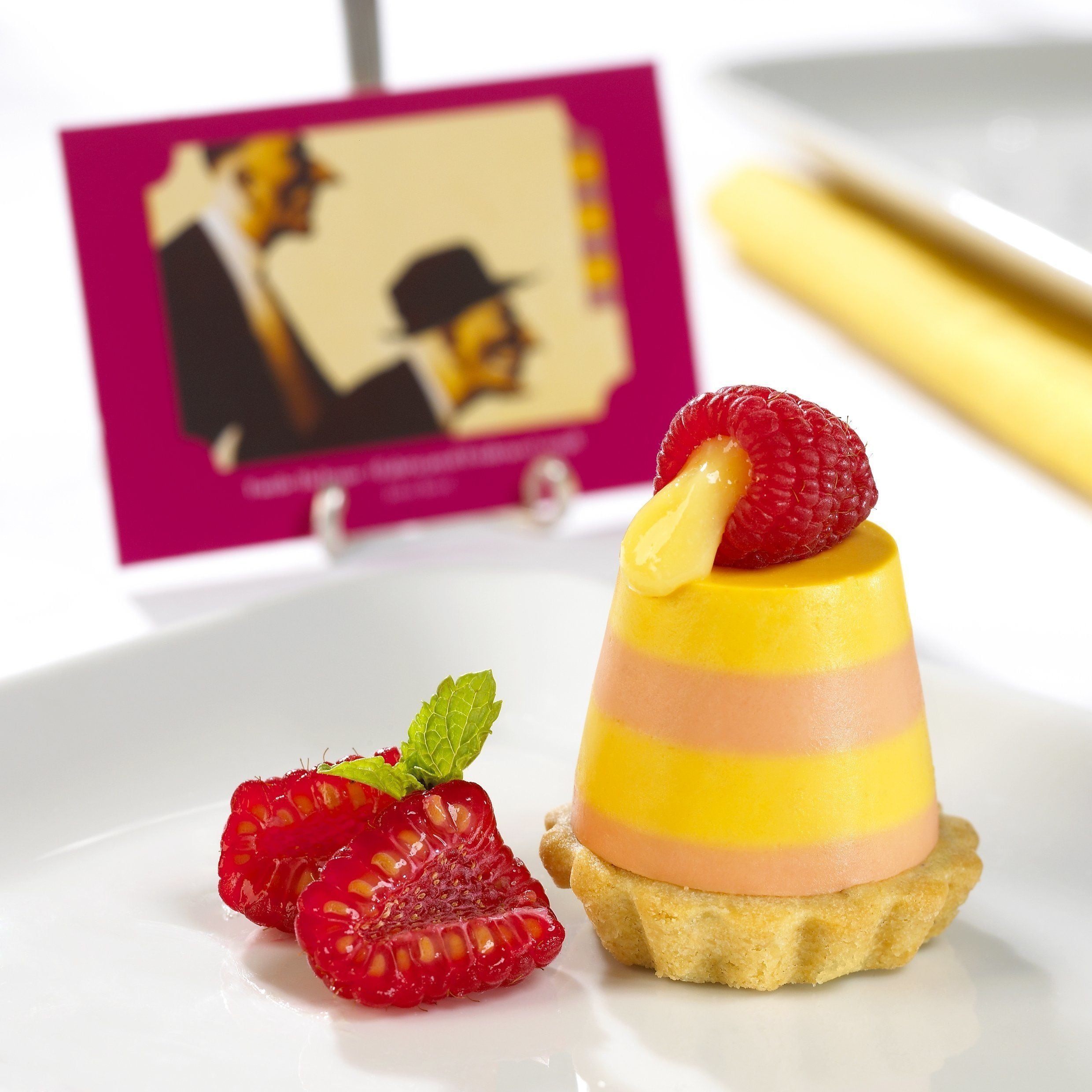A dessert with a raspberry on top, placed on a plate.