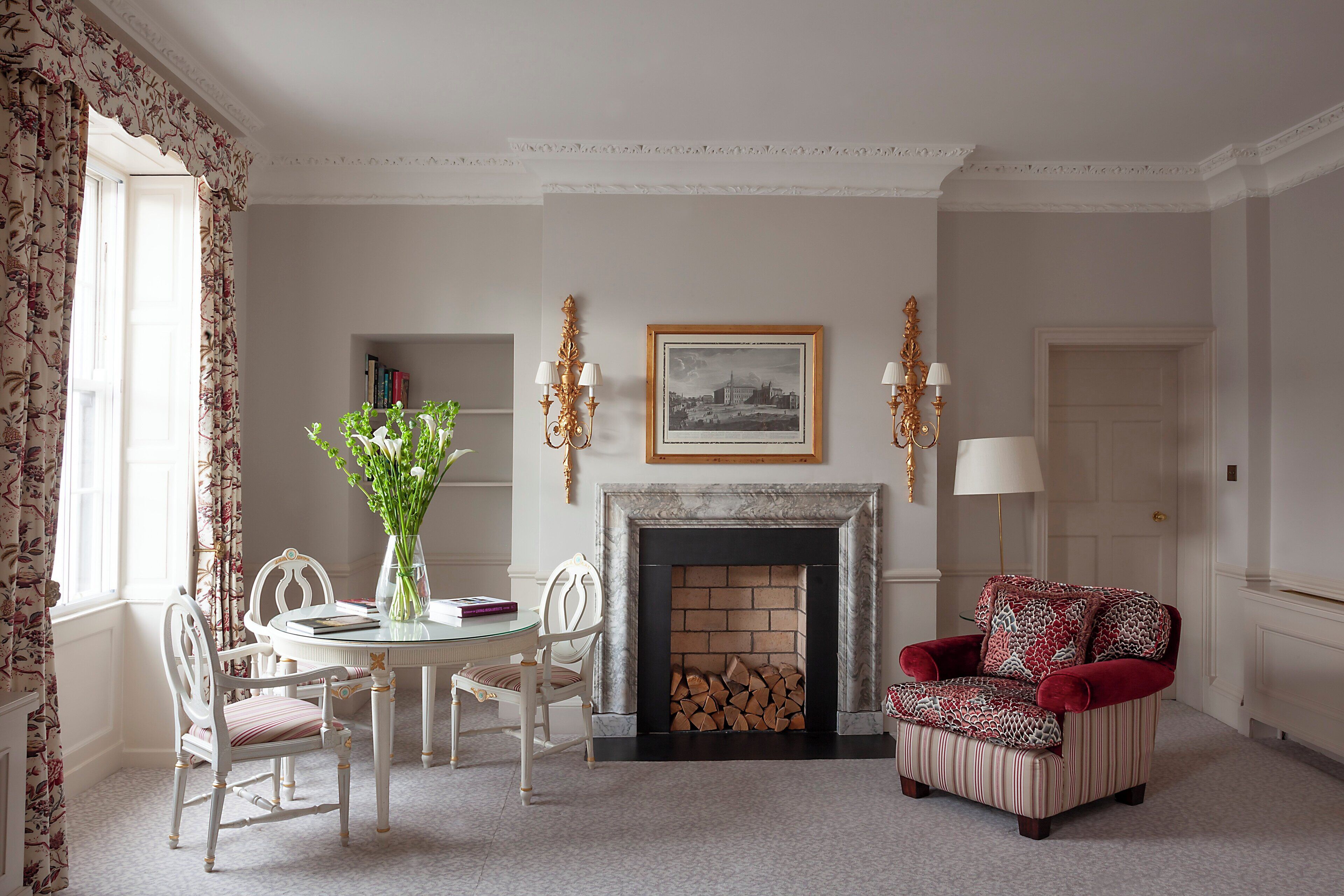 A room with a fireplace, a dining table with chairs, a red armchair, and a bookshelf.