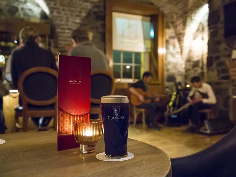 Una mesa de madera con una jarra de cerveza Guinness, un menú y una vela.