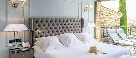 A bedroom with a large bed, bedside lamps, a nightstand, and a view of the outside balcony.