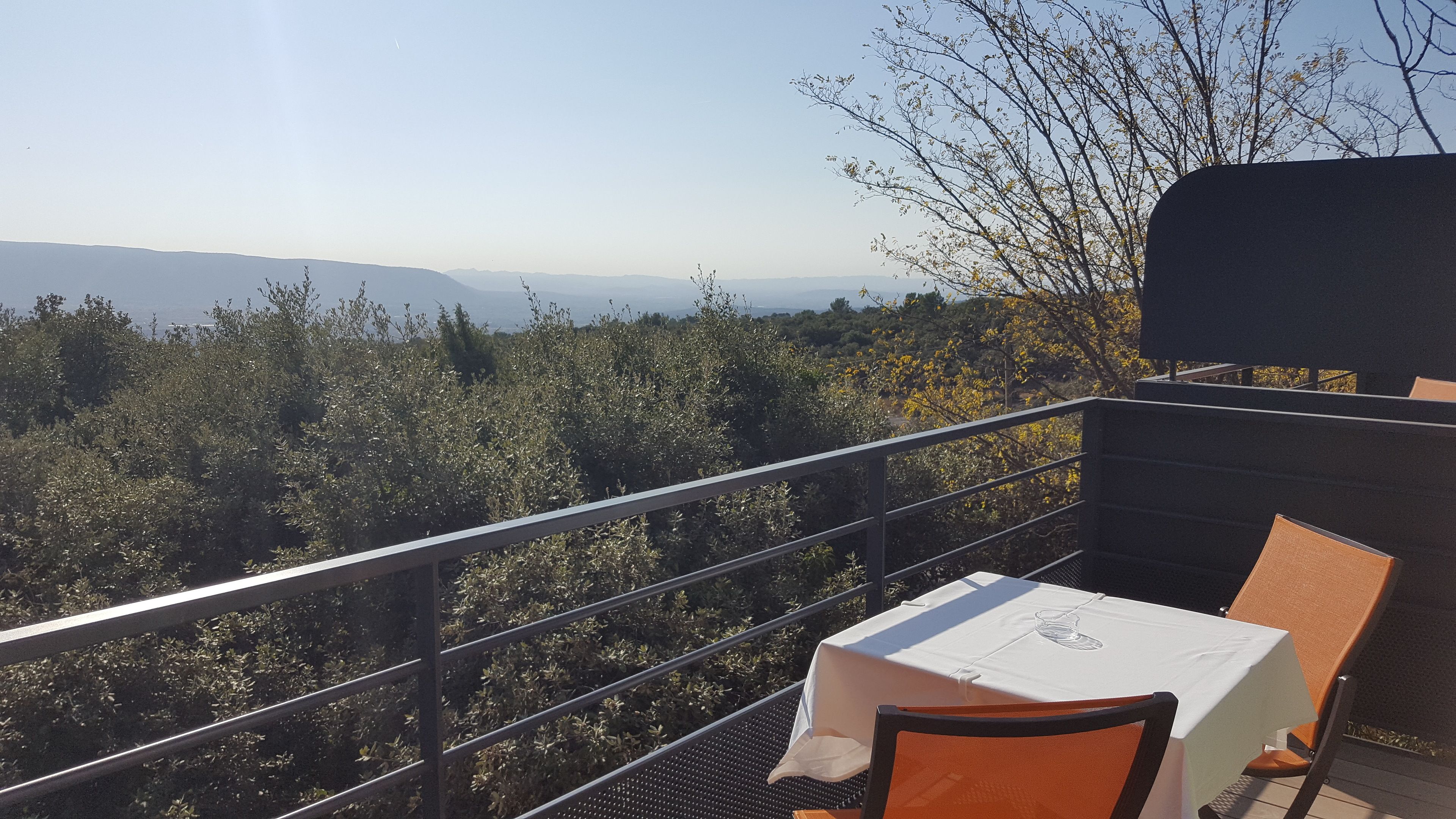 Un balcón con una mesa y una silla, con vista a un paisaje montañoso.