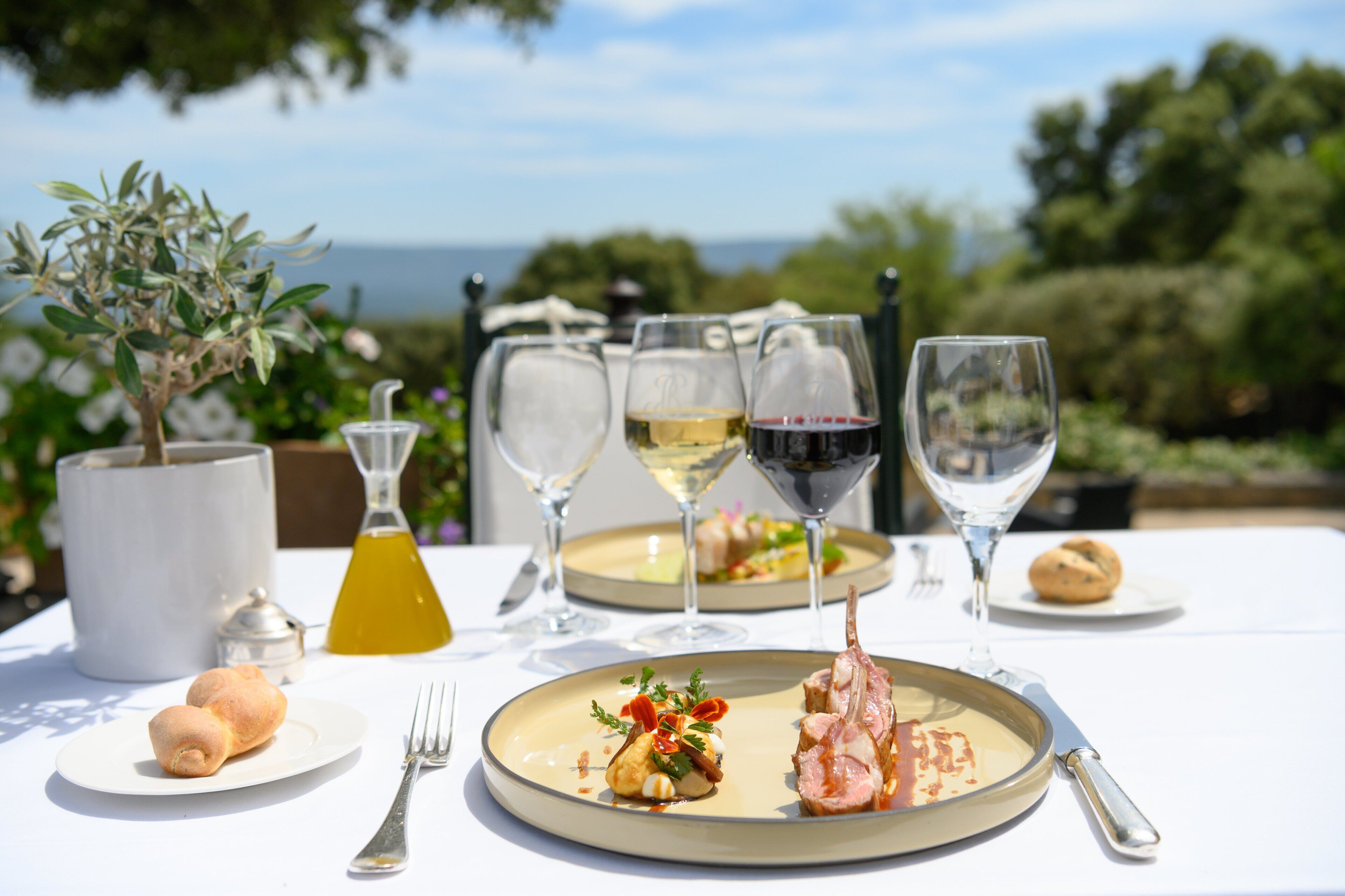 A table set for a meal with plates of food, wine glasses, and a bottle of juice.