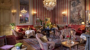 A richly decorated room with a large chandelier, striped wallpaper, and classic furniture.