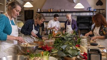 Un grupo de personas en una cocina preparando comida con diferentes verduras e ingredientes sobre la encimera.