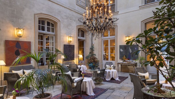 A spacious courtyard with wicker furniture, potted plants, and a chandelier.