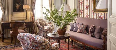 A traditional room with a sofa, armchair, and a small table with a vase.