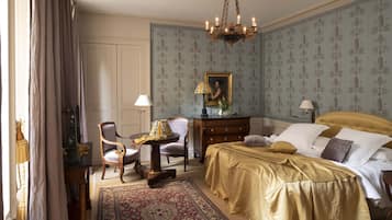 Une chambre à coucher avec un lit, une chaise, une table et un lustre.