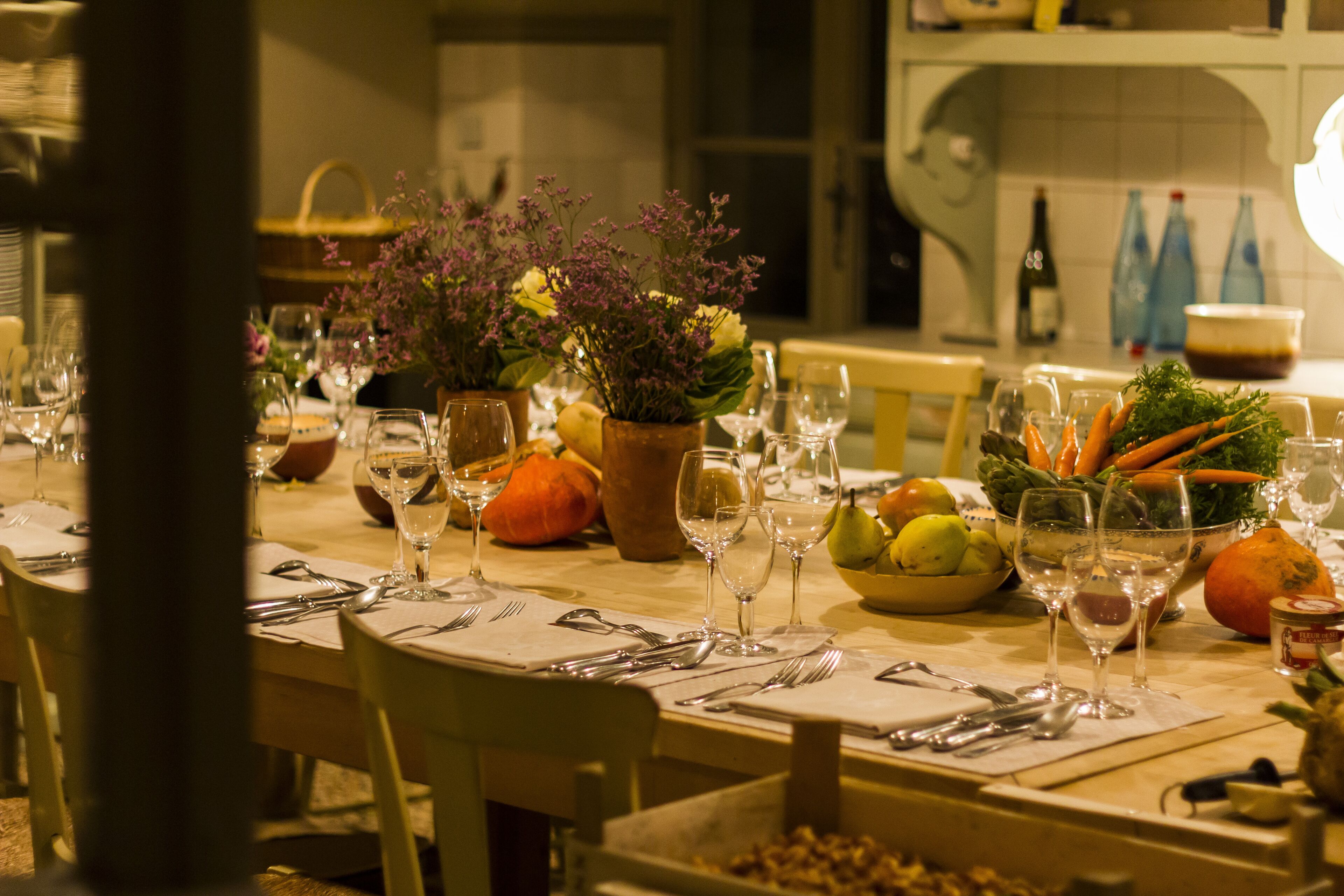 A dining table set with multiple wine glasses, plates, and a bowl of vegetables.