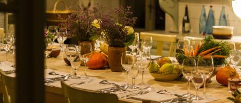 A dining table set with multiple wine glasses, plates, and a bowl of vegetables.