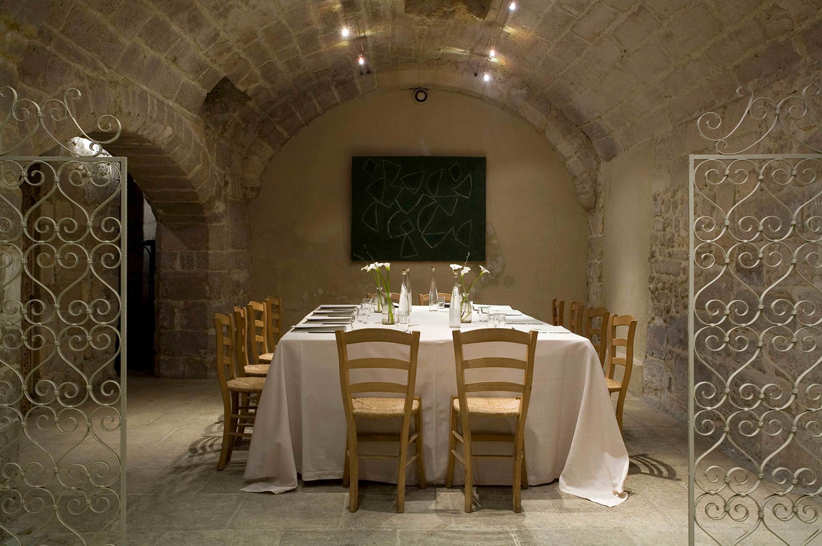 A dining room with a stone arch ceiling, a table set for six, and a green abstract painting on the wall.