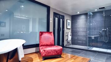 Bathroom features a glass shower enclosure, wall-mounted faucet, and a wooden vanity with a towel rack.