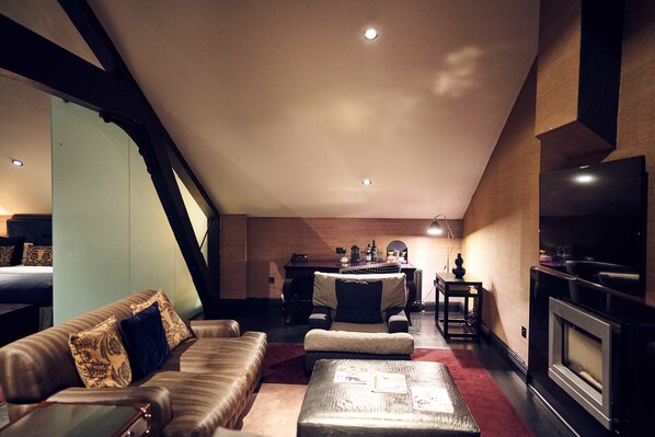 Un salon chaleureux avec un canapé, un pouf et une cheminée.