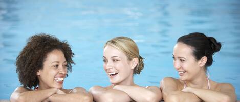 Three individuals resting by a poolside.