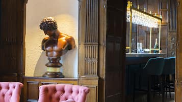 A bar area with a bust sculpture, bar stools, and a chandelier.