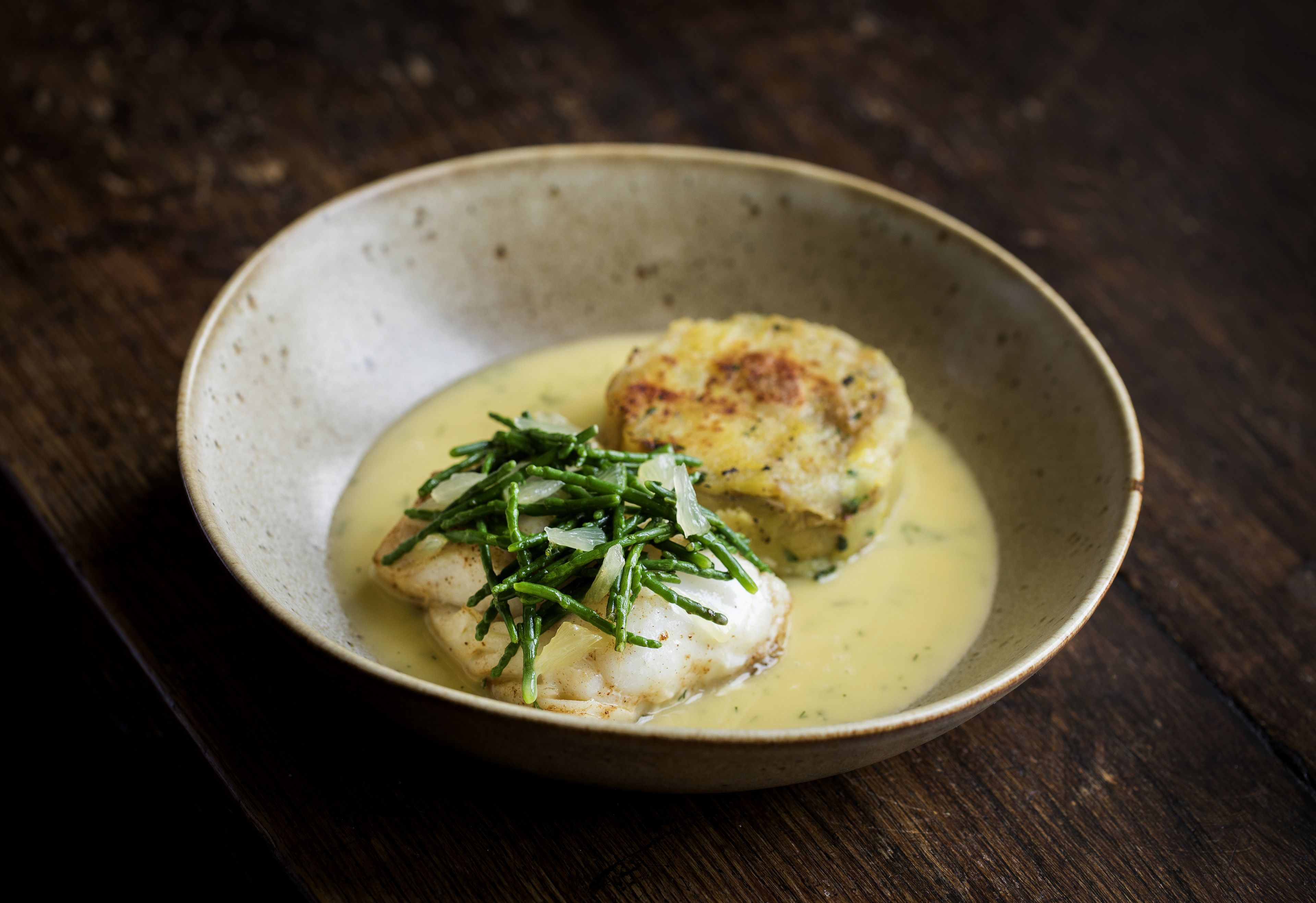 A plate of food with a creamy sauce and green garnish on a rustic wooden table.