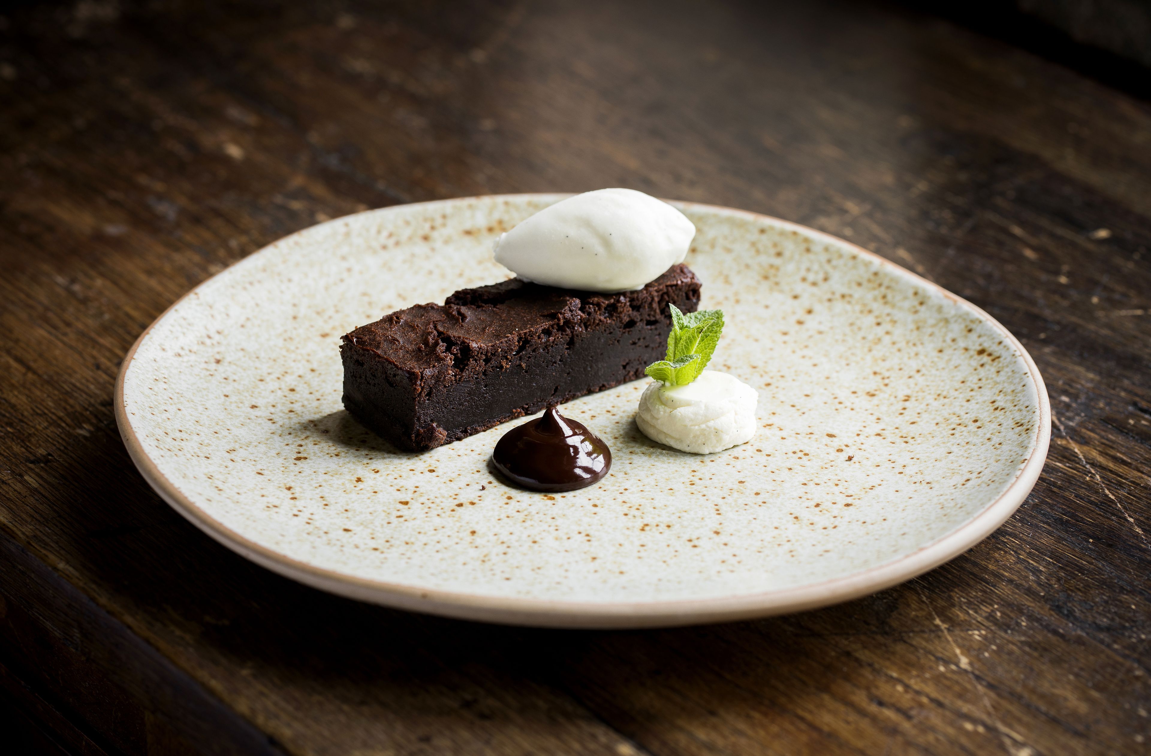 Un postre sobre un plato moteado con un fondo de madera oscura.