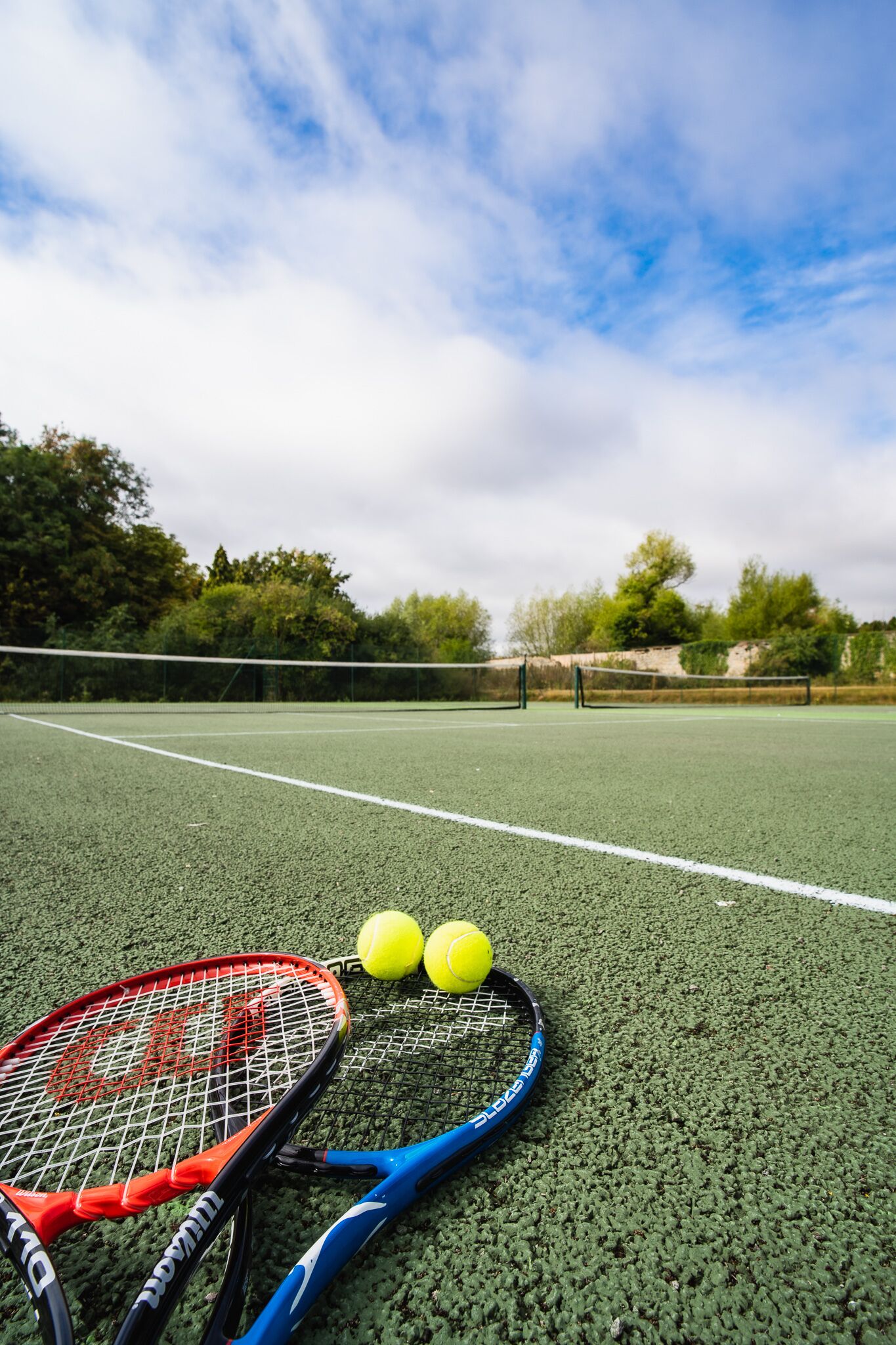 Una cancha de tenis con dos raquetas y dos pelotas.