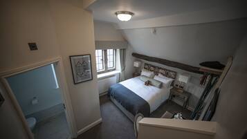 Un dormitorio con una cama grande, una mesita de noche con lámparas, una ventana y vistas al baño.