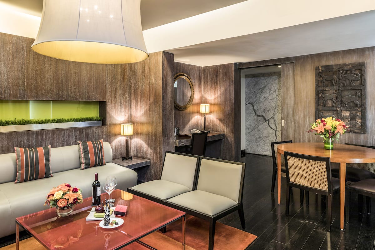 A modern hotel room with a sofa, a dining table, and a chandelier.