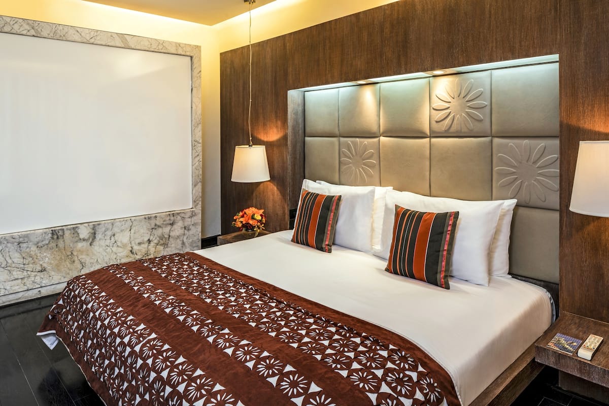 A hotel room with a large bed, a marble wall, and a wooden headboard.