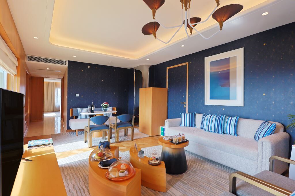 Una habitación de hotel moderna con sofá, mesa de centro y comedor.