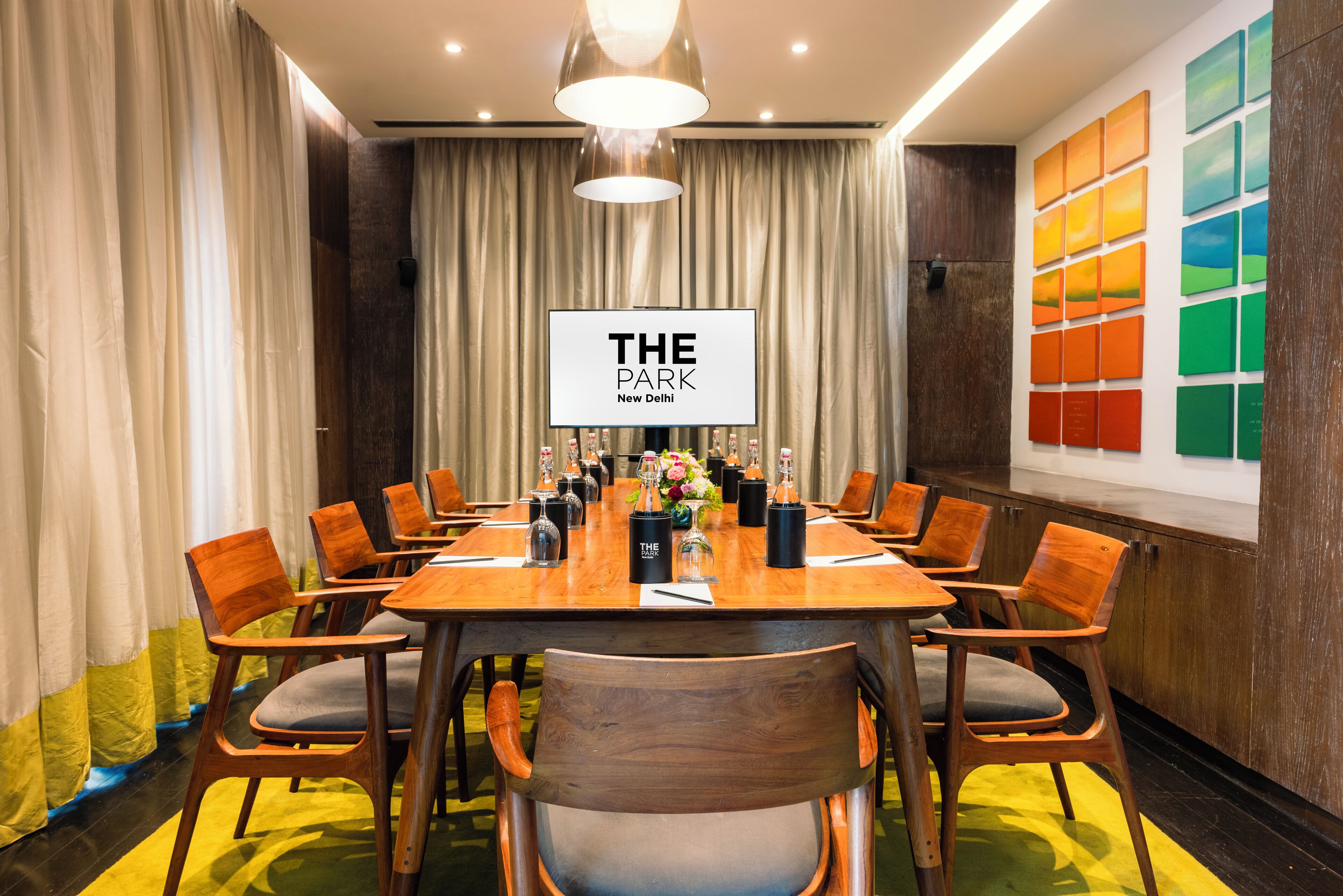 Ein Konferenzraum mit einem langen Tisch, Holzsesseln und einem Schild mit der Aufschrift 'THE PARK New Delhi'.