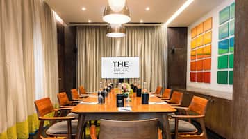 Ein Konferenzraum mit einem langen Tisch, Holzsesseln und einem Schild mit der Aufschrift 'THE PARK New Delhi'.