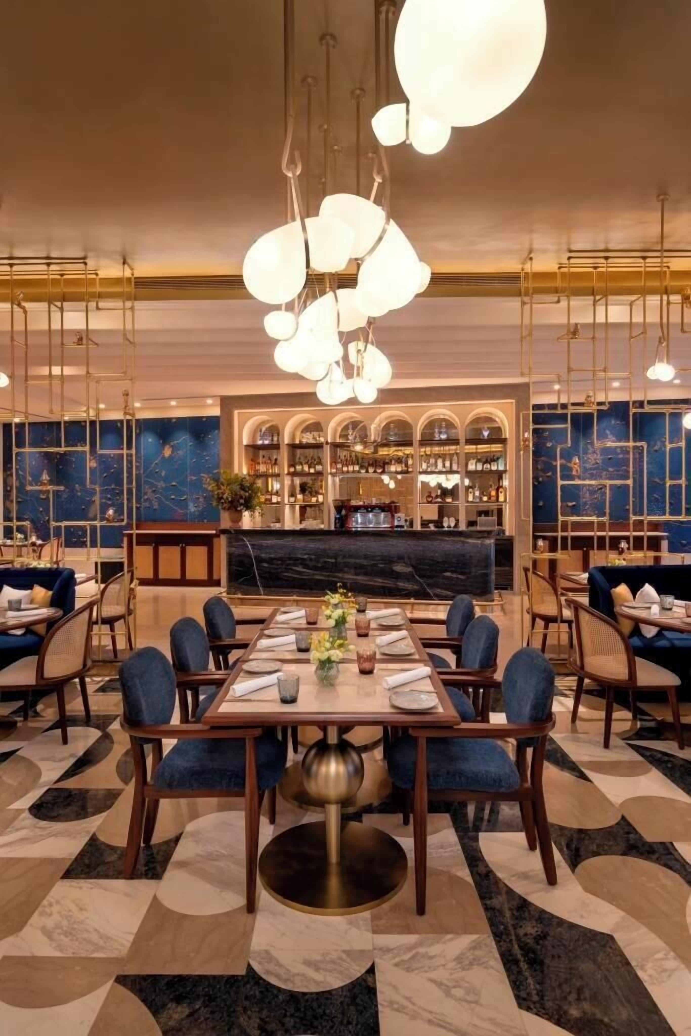 A restaurant with a marble floor, blue seating, and a bar area.