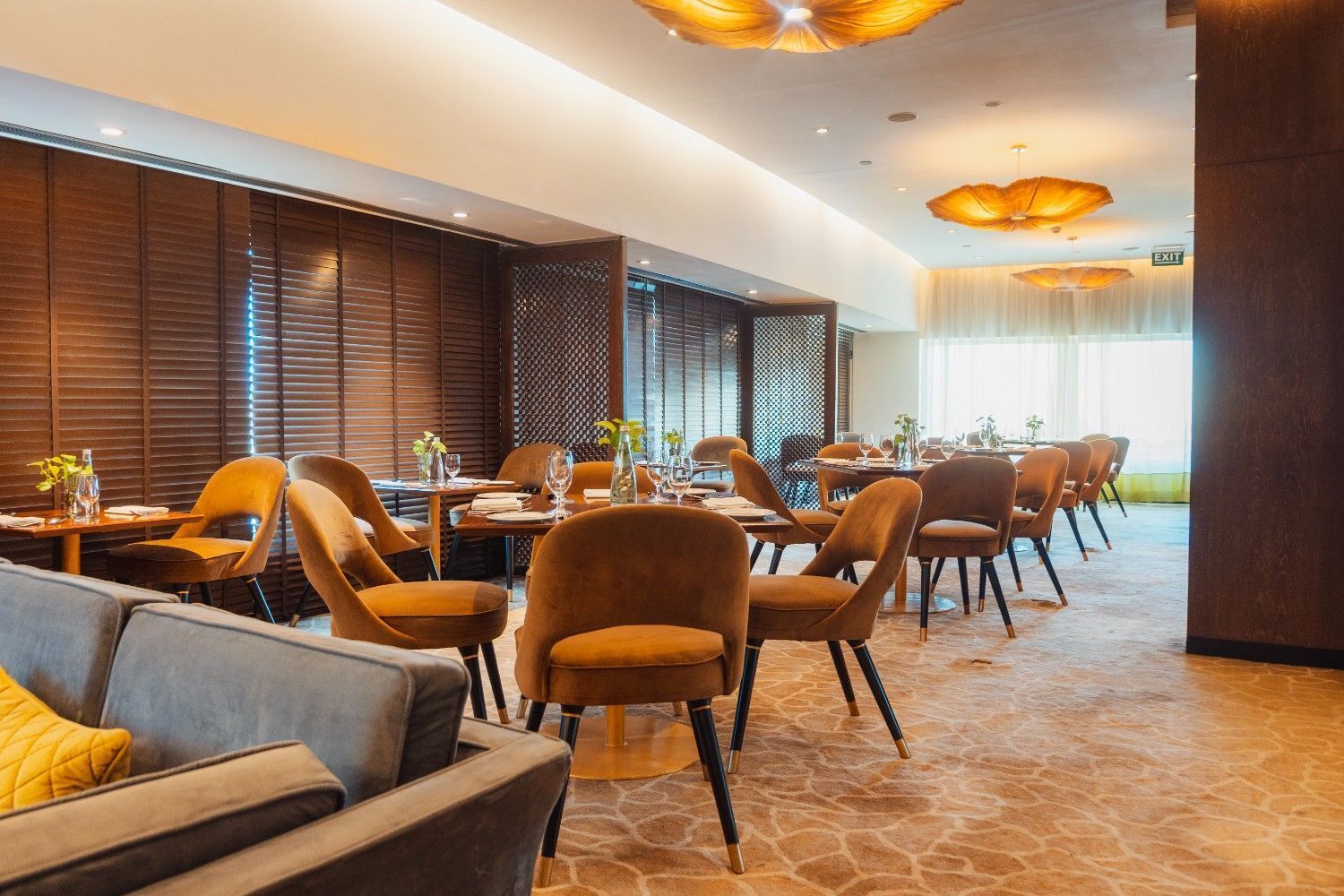A modern dining area with wooden paneling, orange chairs, and a stone floor.