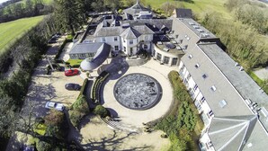 An aerial view of a large, modern building with a circular courtyard, surrounded by parking and greenery. - The Vineyard (Newbury)