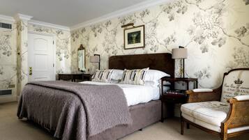 A bedroom with a large bed, a nightstand, a chair, and a dresser.