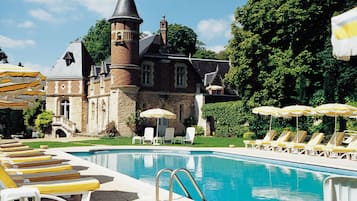 Una piscina al aire libre, sombrillas, sillones reclinables de piscina