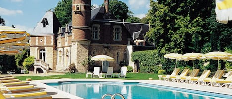 Una piscina al aire libre, sombrillas, sillones reclinables de piscina