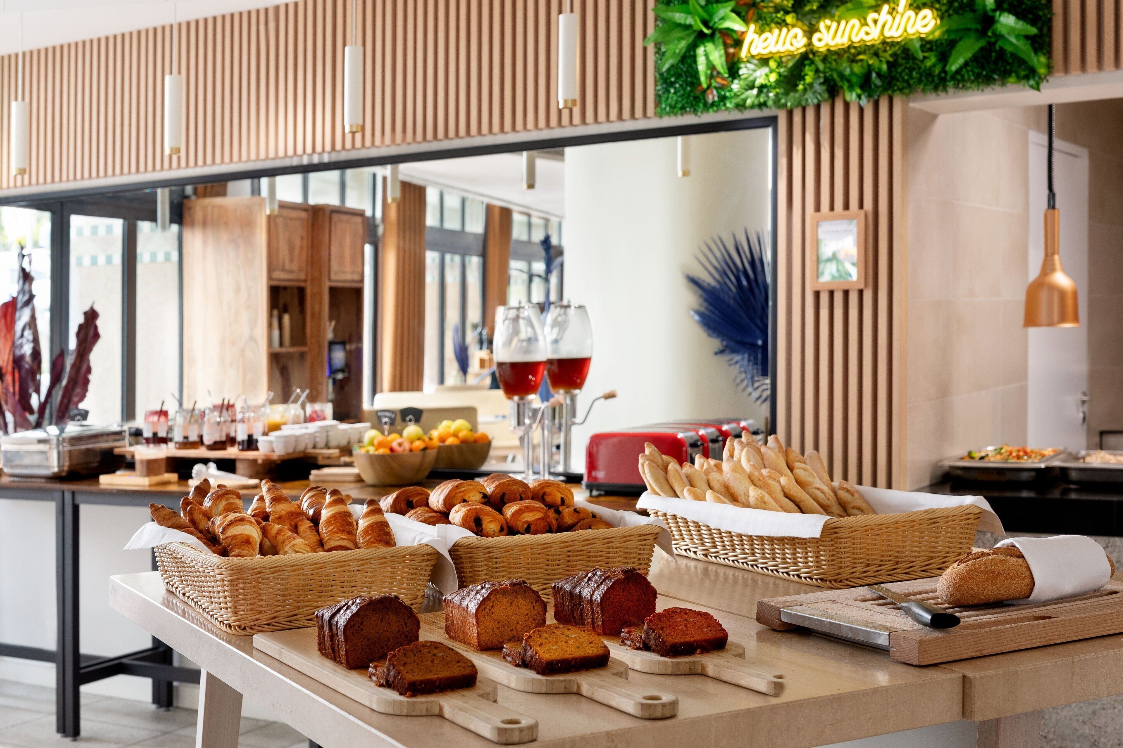A buffet with various breads, pastries, and a cutting board with a knife.