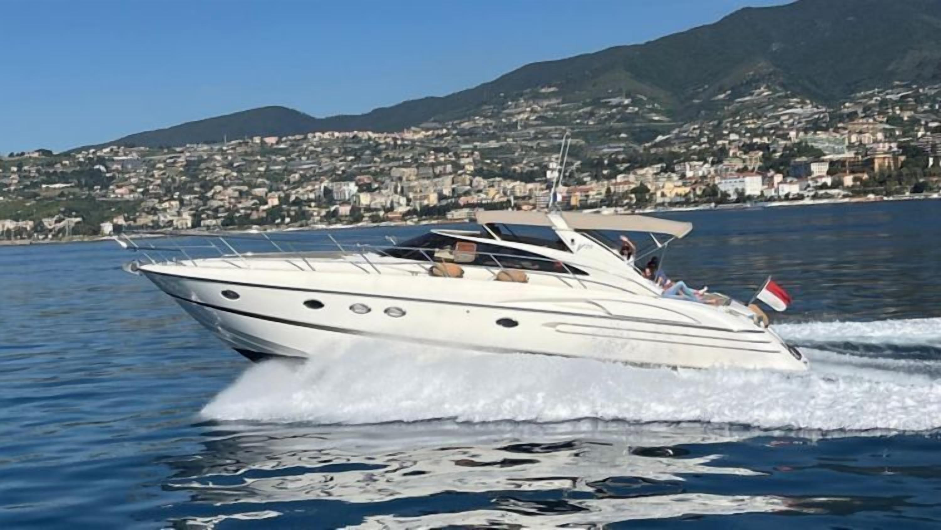 A speedboat on water with a mountainous town in the background.