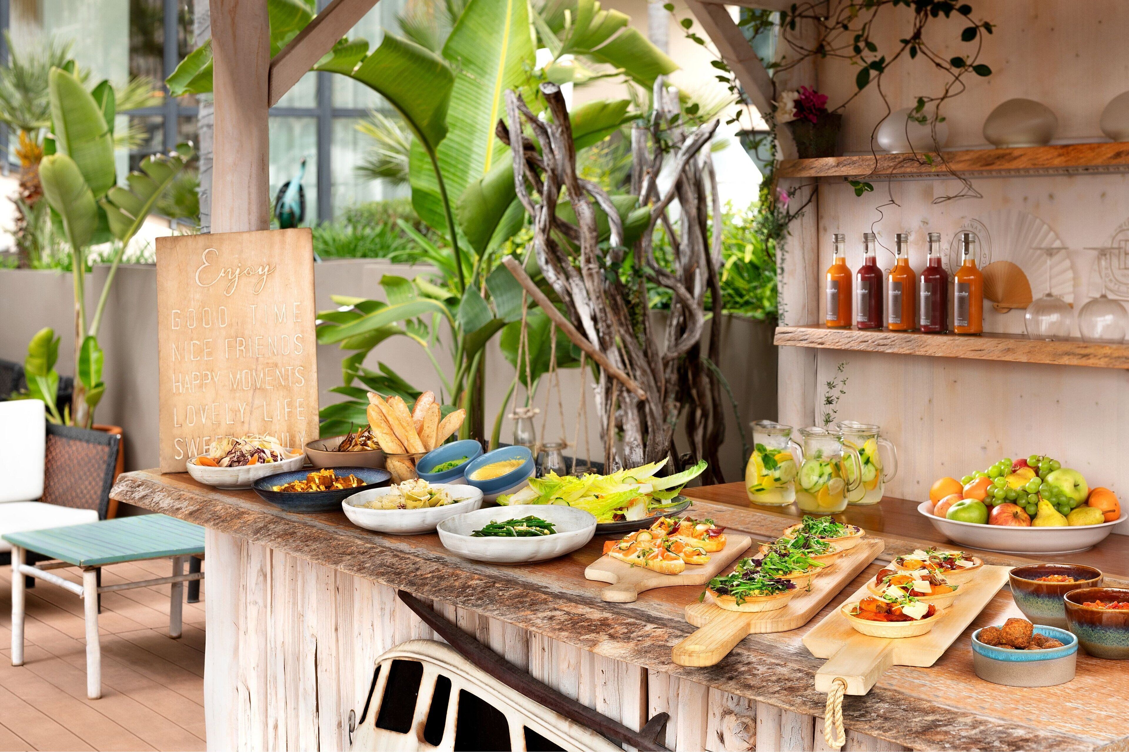 A well-organized outdoor dining area with various dishes, drinks, and a rustic wooden counter.
