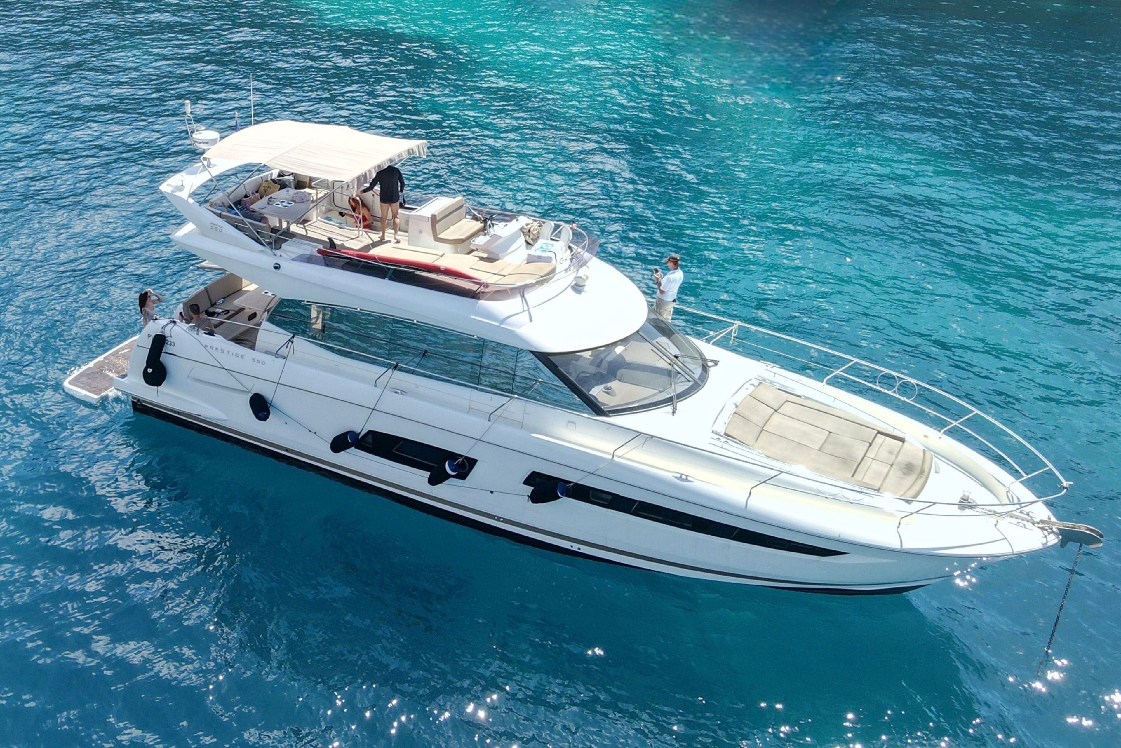 A white yacht with a covered upper deck, multiple seating areas, and a visible cabin.