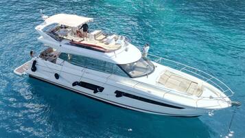 A white yacht with a covered upper deck, multiple seating areas, and a visible cabin.
