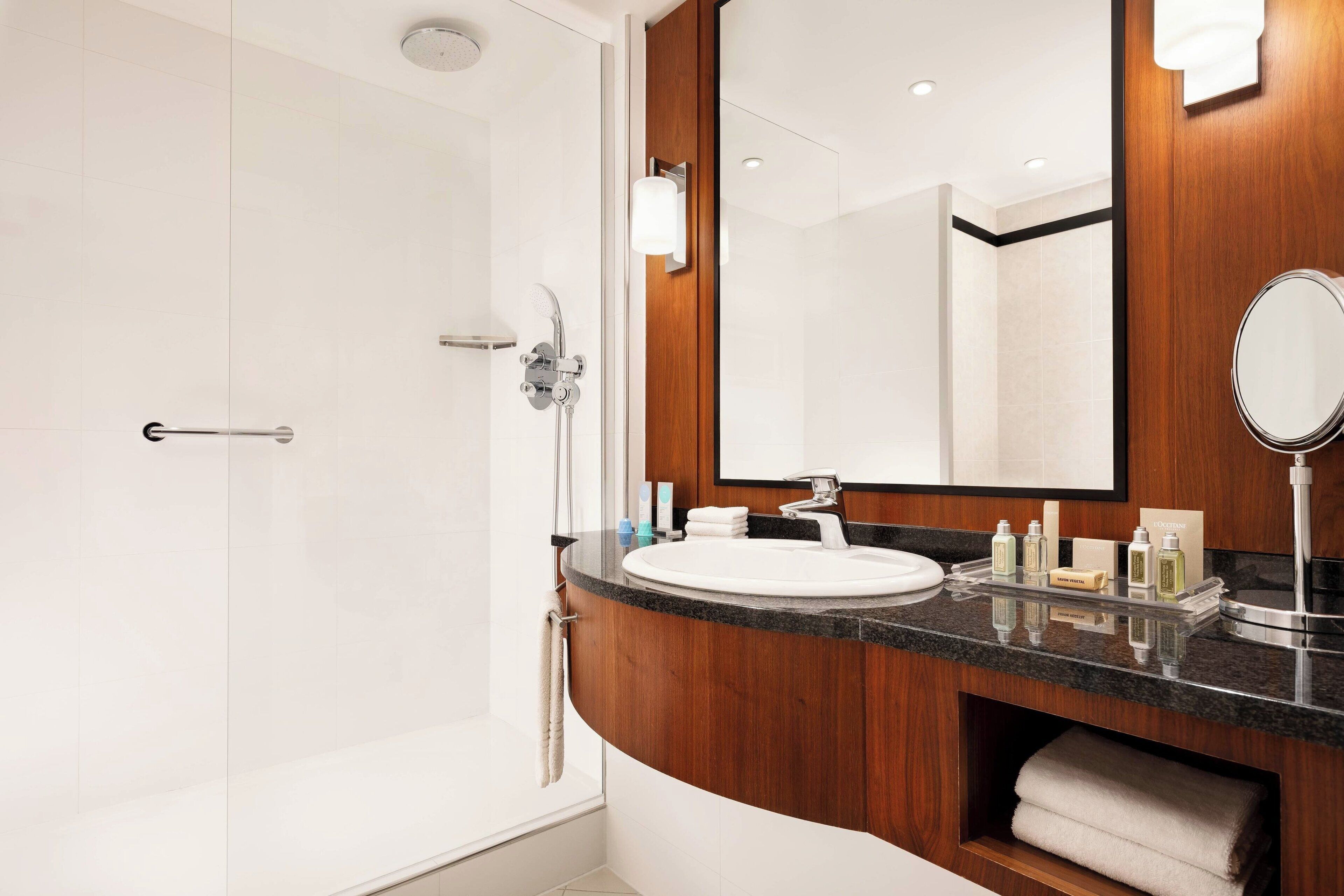 A modern bathroom with a white sink, a large mirror, and a shower area.